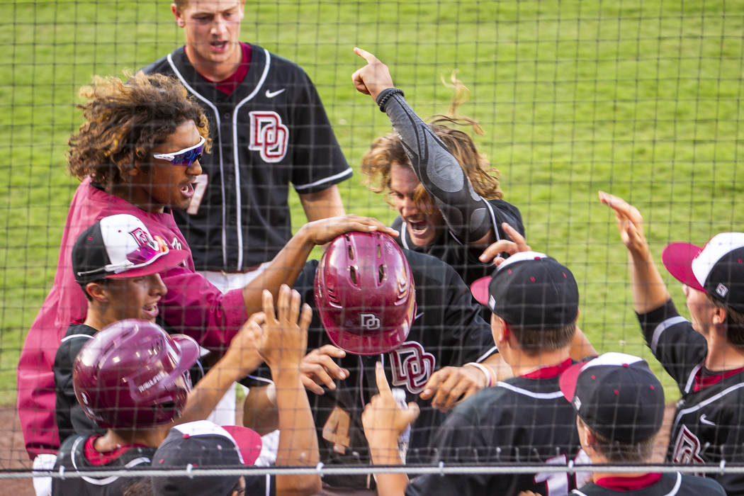 Desert Oasis players congratulate Parker Schmidt (4), center, on another run against Reno duri ...