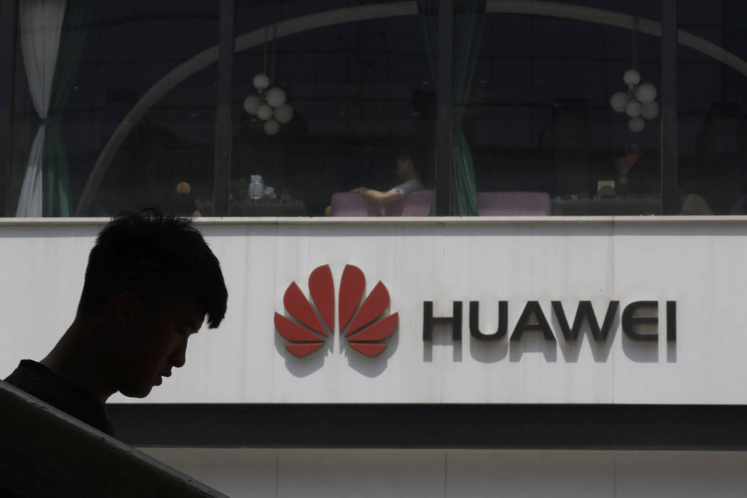 A Chinese man is silhouetted near the Huawei logo in Beijing on Thursday, May 16, 2019. In a fa ...