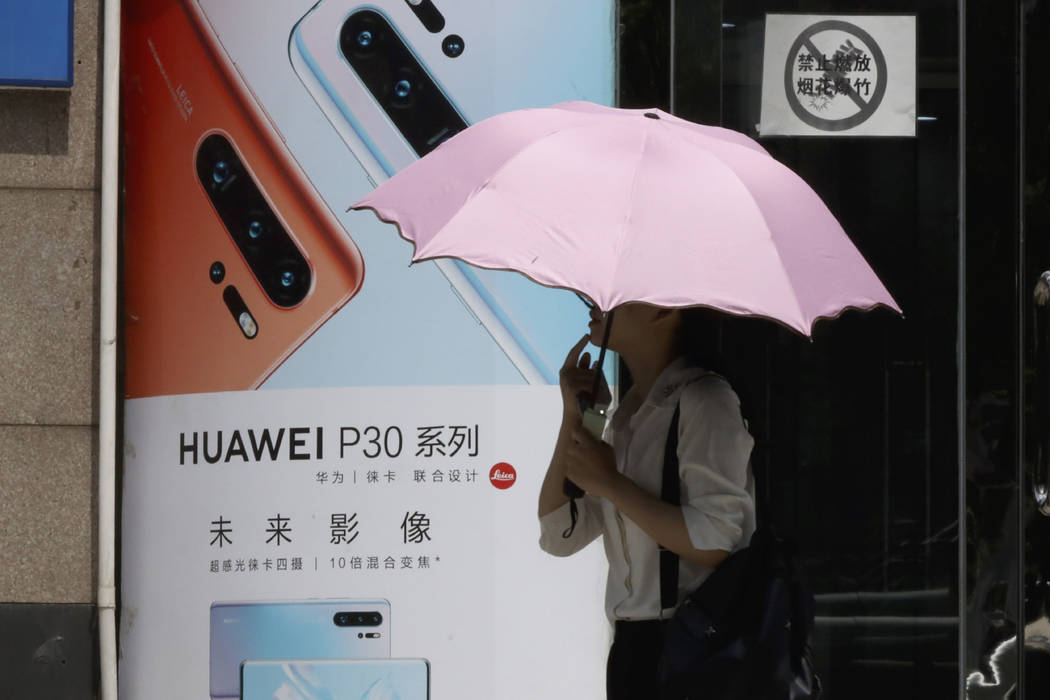 A woman walks past advertisement for Huawei smartphones in Beijing on Thursday, May 16, 2019. I ...