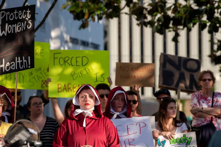 Margeaux Hartline, dressed as a handmaid, protests against a ban on nearly all abortions outsid ...