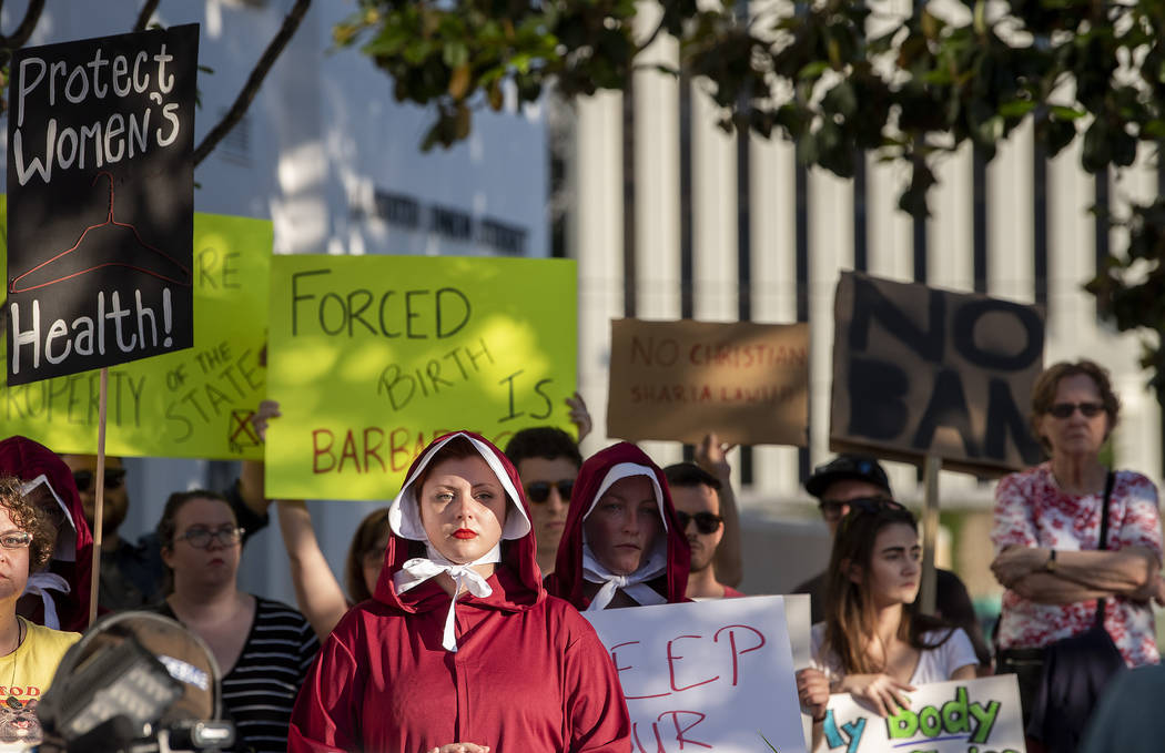 Margeaux Hartline, dressed as a handmaid, protests against a ban on nearly all abortions outsid ...