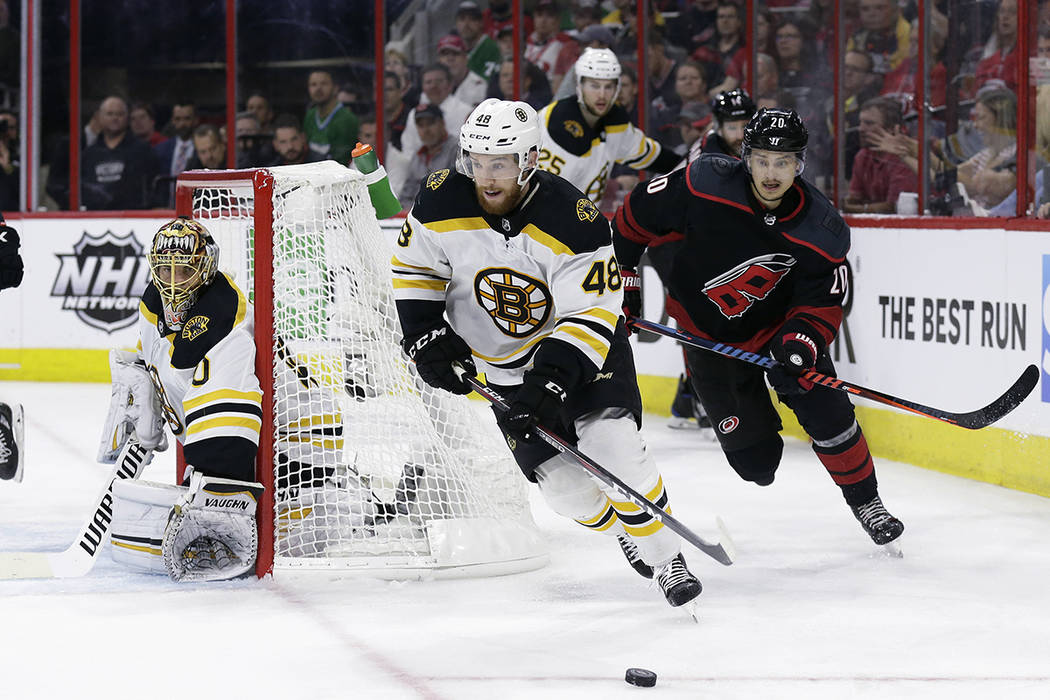 Boston Bruins' Matt Grzelcyk (48) controls the puck against a chasing Carolina Hurricanes' Seba ...