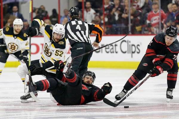 Boston Bruins' Sean Kuraly (52) and Carolina Hurricanes' Greg McKegg struggle during a face-off ...