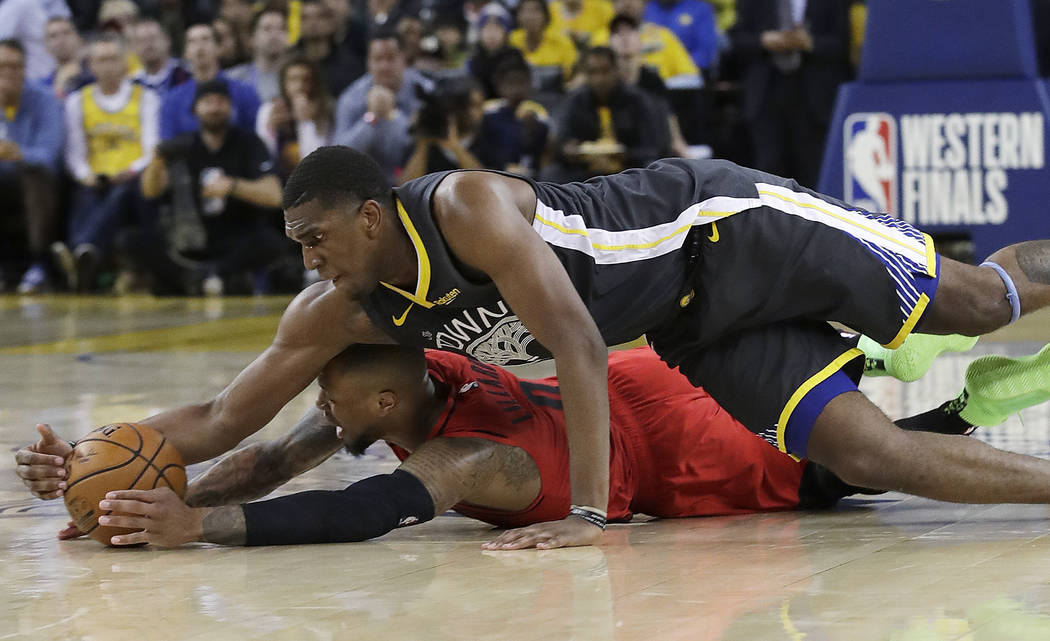 Golden State Warriors center Kevon Looney, top, reaches for the ball over Portland Trail Blazer ...