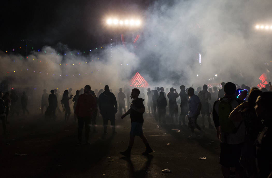 Attendees are silhouetted by the Wasteland stage during the first day of the Electric Daisy Car ...