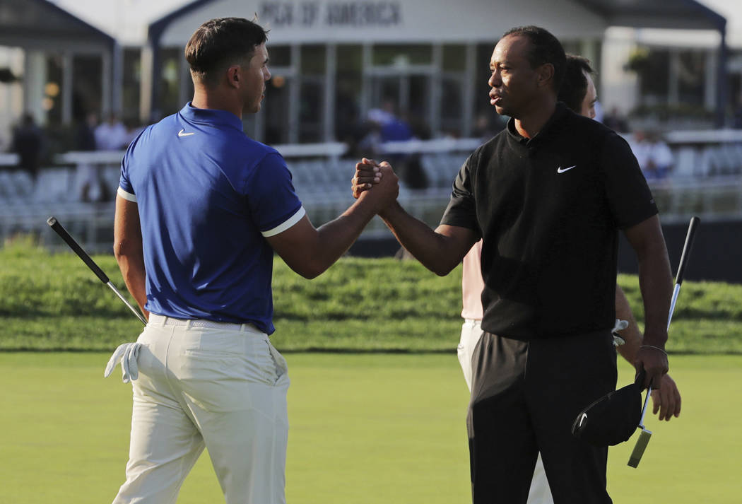 Brooks Koepka, left, shakes hands with Tiger Woods after finishing the second round of the PGA ...