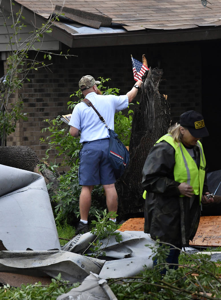 Letter carrier James Hurtado resets a small U.S. flag into a tree stump while delivering the ma ...