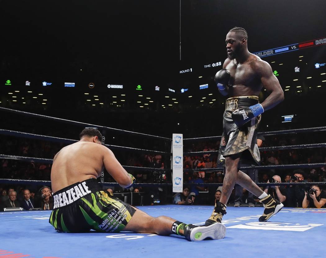 Deontay Wilder, right, knocks down Dominic Breazeale during the first round of a WBC heavyweigh ...