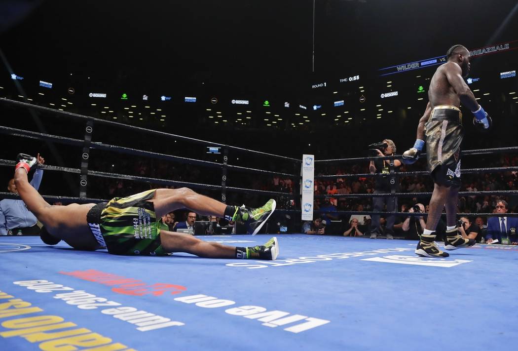 Deontay Wilder, right, knocks down Dominic Breazeale during the first round of the WBC heavywei ...