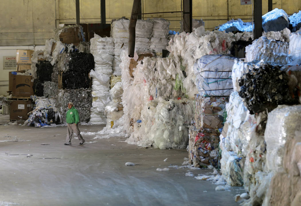 In this May 7, 2019 photo, a man walks under towers of recyclables at a GDB International wareh ...