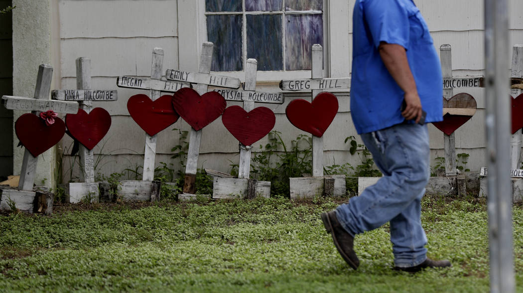 A man passes old memorial crosses on the side of a church building following a dedication cerem ...