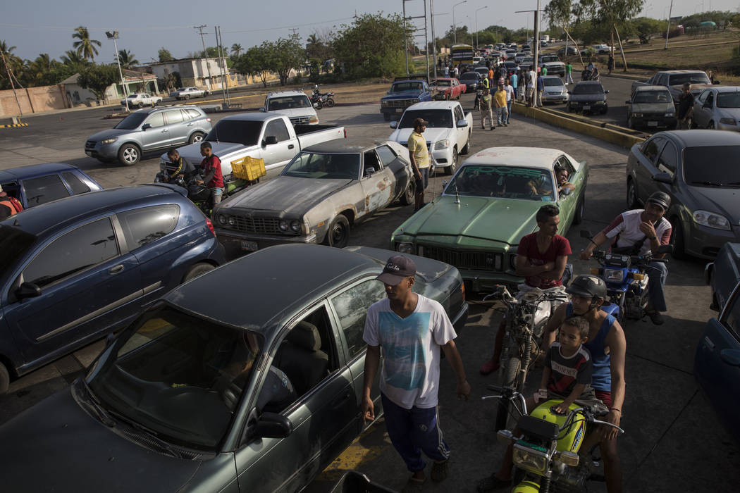 A line of cars spills on to the street as drivers wait to fill their tanks at a fuel station in ...