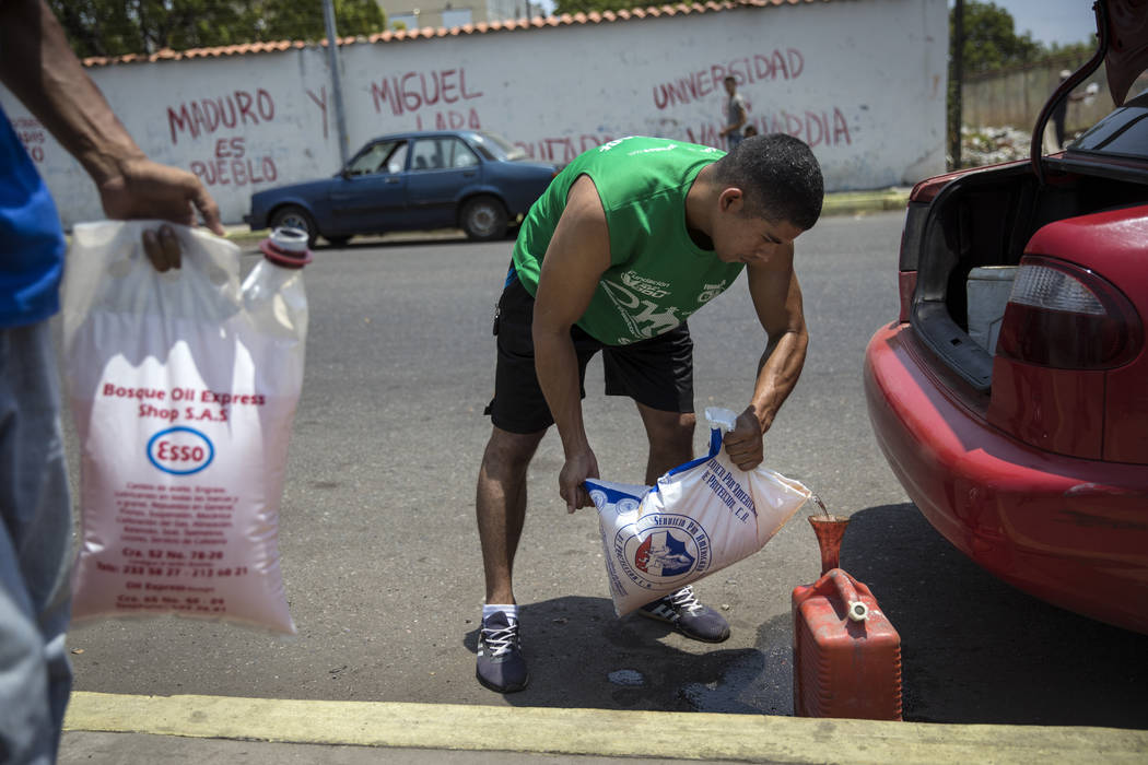 Jesus Gonzales fills a container with bagged gasoline he bought at extra cost at a fuel station ...