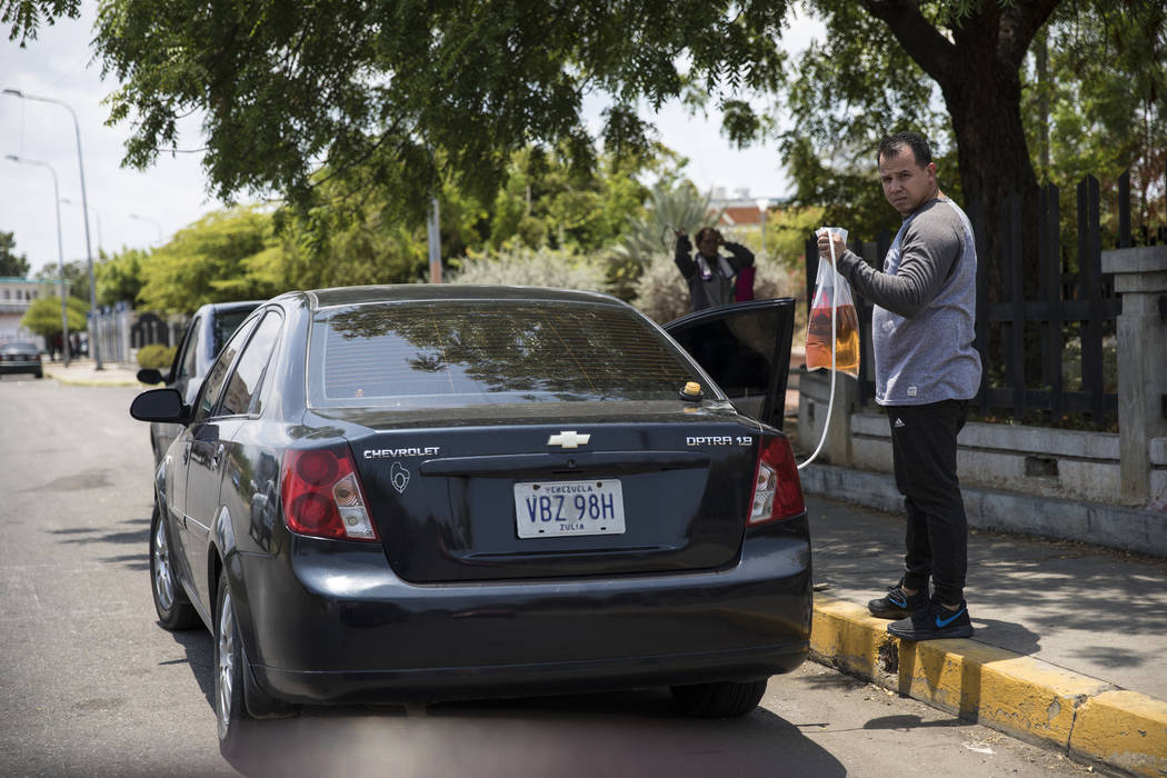 A man fills his tank with bagged gasoline he bought at extra cost at the fuel station, in order ...