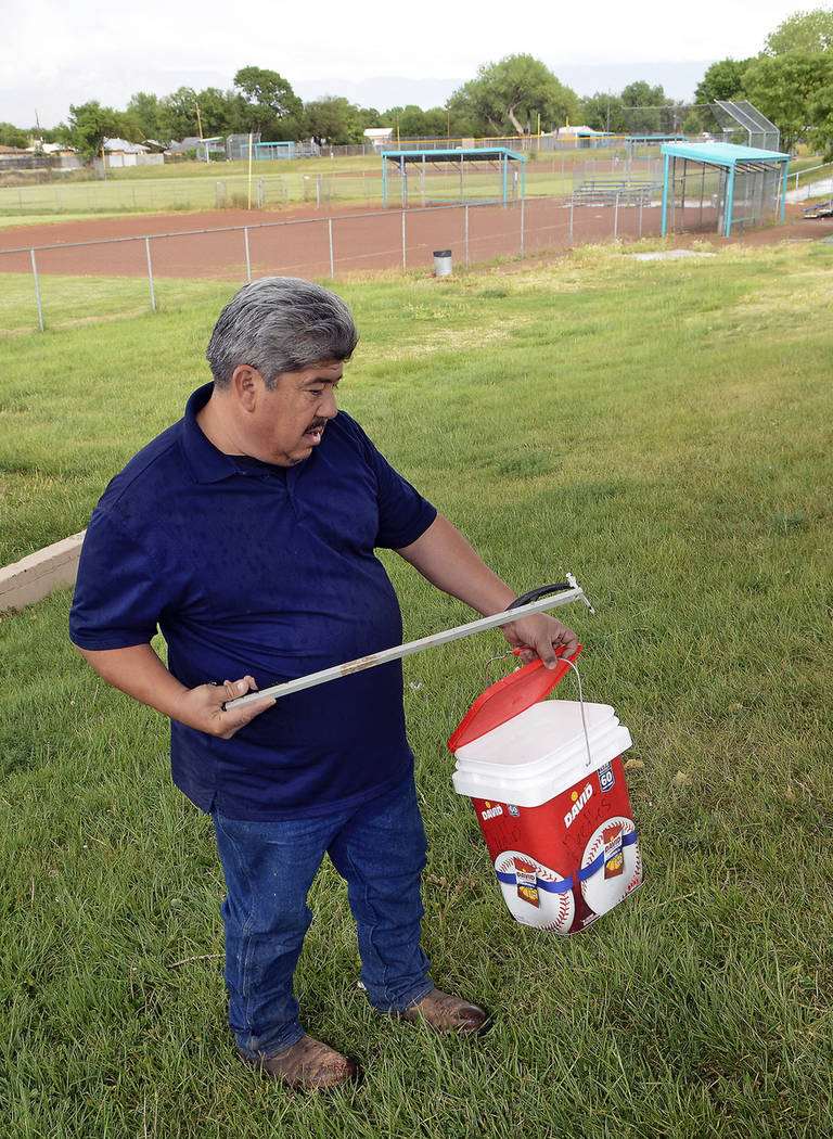 Hector Aguilar uses a claw grabber extension to remove a hypodermic needle from one of the base ...