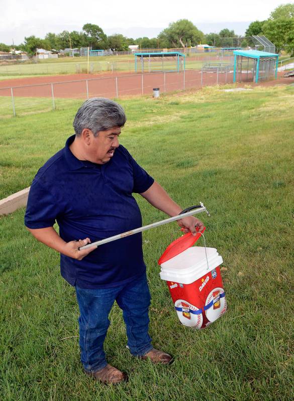 Hector Aguilar uses a claw grabber extension to remove a hypodermic needle from one of the base ...