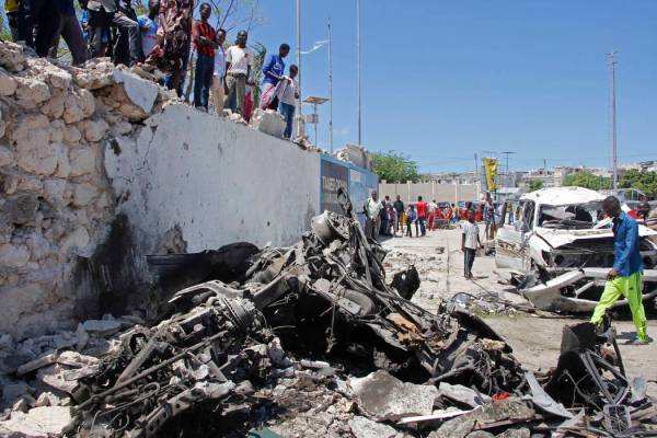 Somalis look at the wreckage after a suicide car bomb attack in the capital Mogadishu, Somalia ...