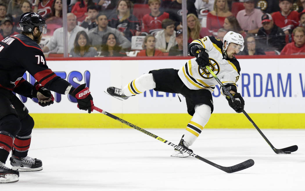 Boston Bruins' Brad Marchand (63) takes a shot on goal while Carolina Hurricanes' Jaccob Slavin ...