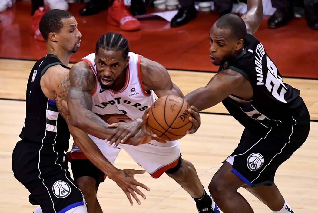 Toronto Raptors forward Kawhi Leonard (2) works between Milwaukee Bucks' George Hill, left, and ...