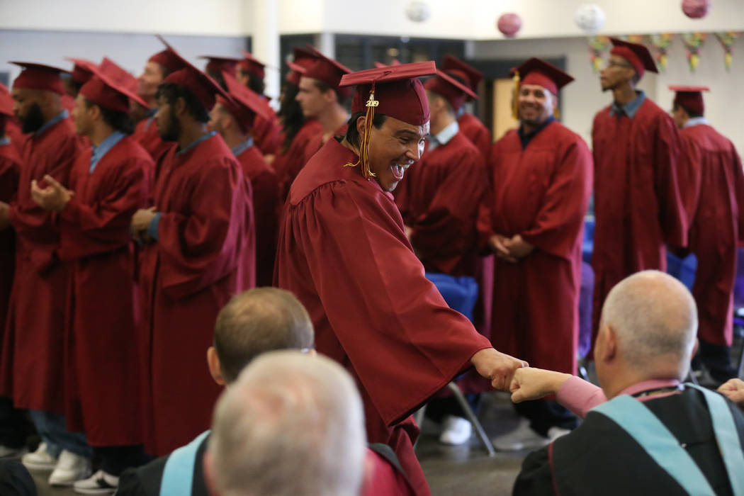 Inmate Paul Ortega, 35, fist bumps math teacher Bill Fisher during his graduation ceremony from ...