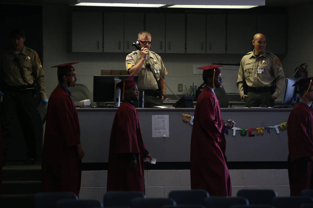 Prison guards watch over inmates as they make their way to their graduation at the High Desert ...