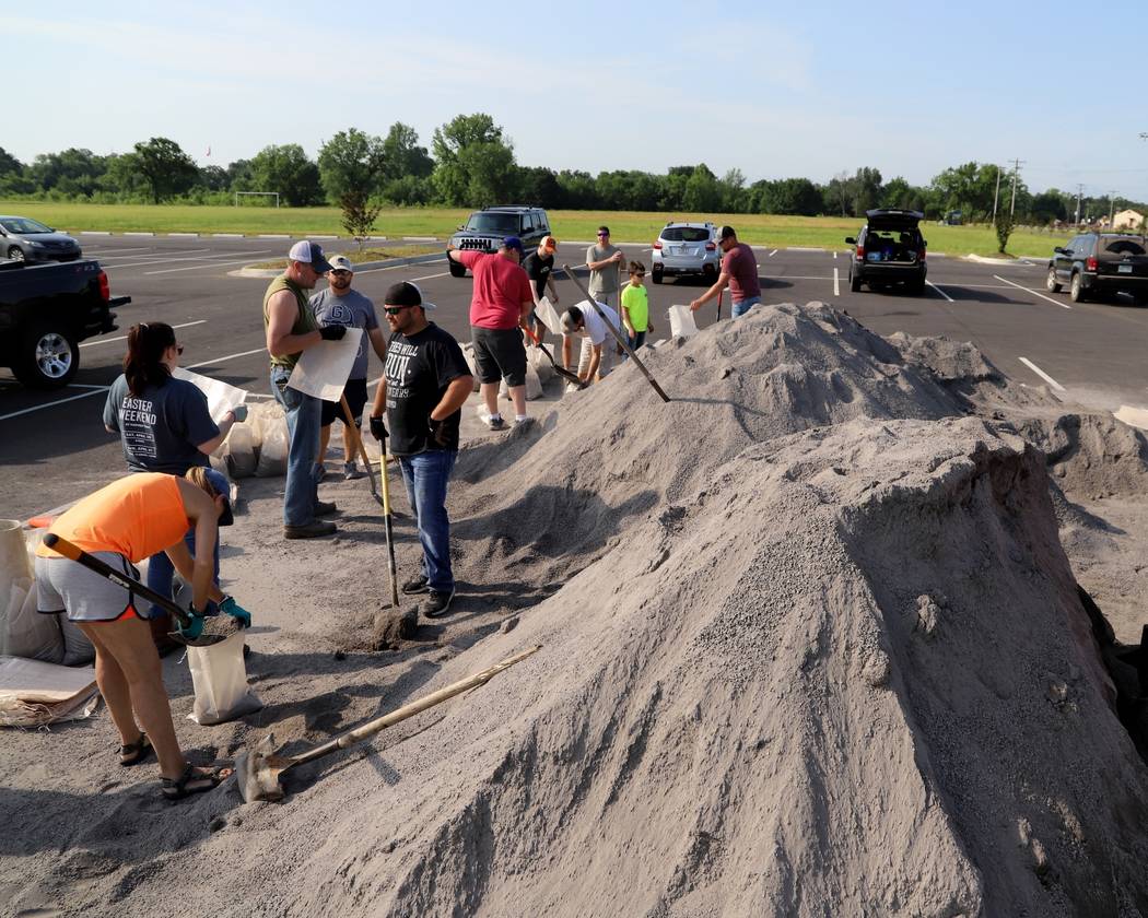 Volunteers fill sand bags at the soccer field parking lot in Chaffee Crossing, Ark., Saturday, ...