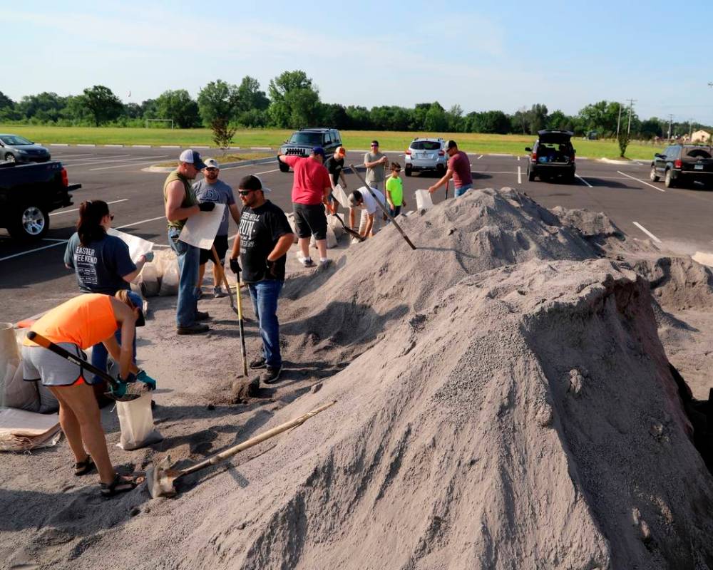 Volunteers fill sand bags at the soccer field parking lot in Chaffee Crossing, Ark., Saturday, ...