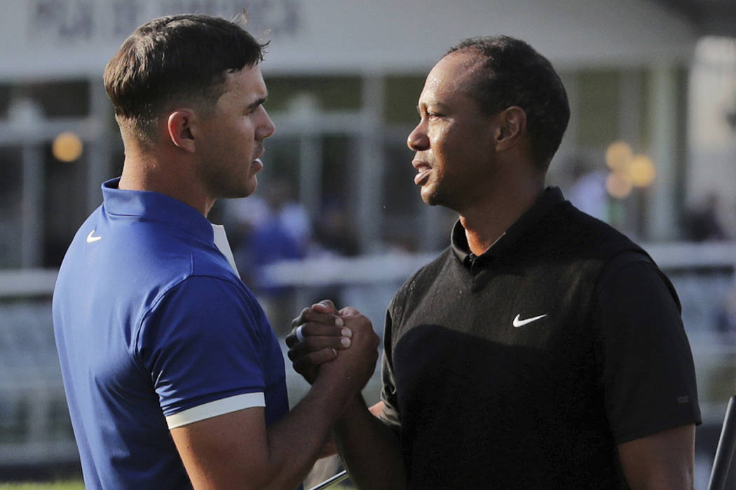 Brooks Koepka, left, shakes hands with Tiger Woods after finishing the second round of the PGA ...