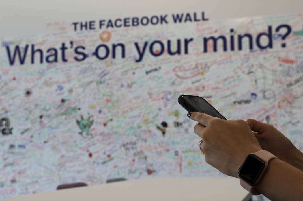 In this Monday, May 20, 2019 photo, a woman uses her mobile at the Facebook office in Dubai, Un ...