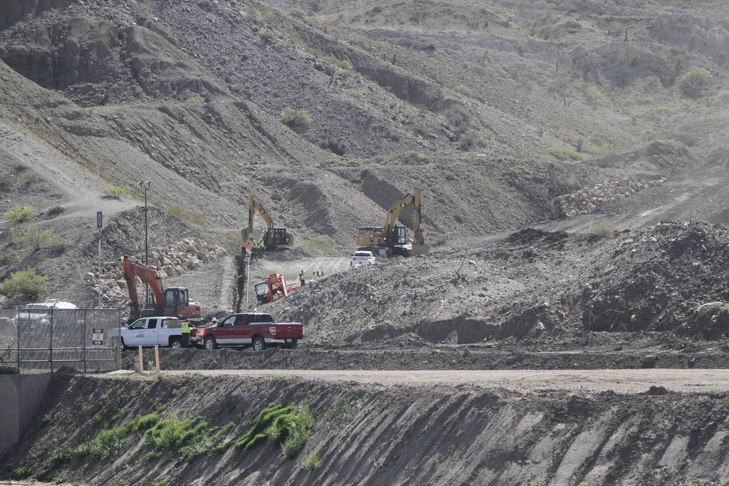 In a May 24, 2019 photo, construction workers prepare footers for sections of bollard-style fe ...