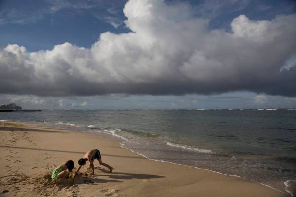 FILE - In this Aug. 25, 2015, file photo two children visiting from China play on Waikiki Beach ...