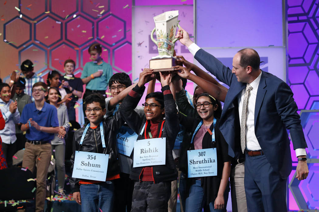 E.W. Scripps CEO Adam Symson, right, presents a trophy to the eight co-champions of the Scripps ...