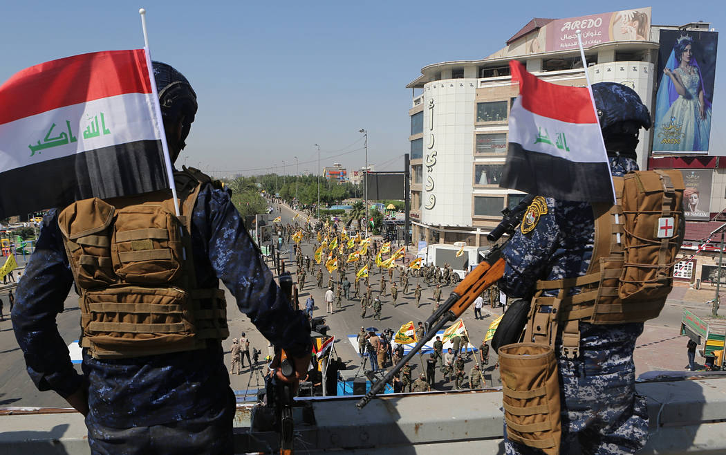 Federal police officers stand guard while Popular Mobilization Forces march during "al-Qud ...