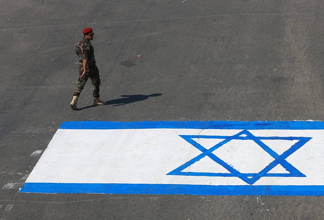 A fighter with Iraqi Popular Mobilization Forces walks past a representation of an Israeli flag ...