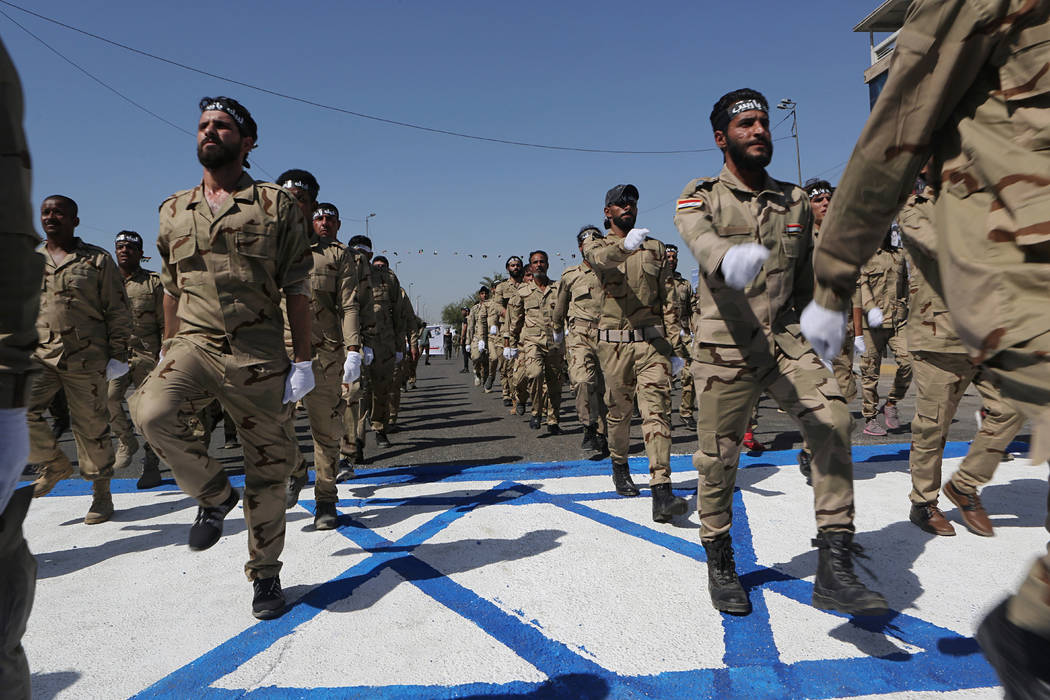 Iraqi Popular Mobilization Forces march over a representation of an Israeli flag during "a ...