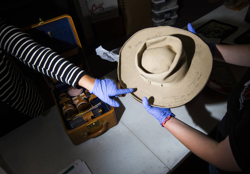 Doctoral student Paige Figanbaum, left, points to a cowboy hat with written markings referencin ...