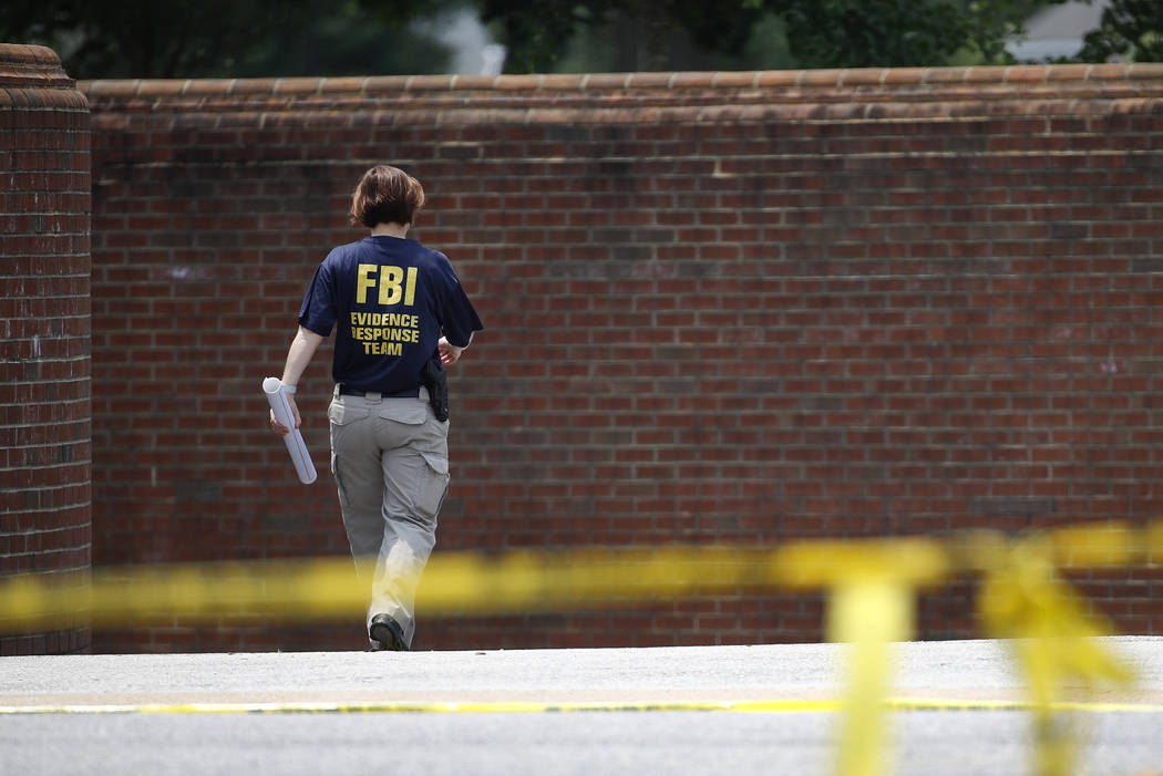 A member of the FBI walks down a ramp to enter a municipal building that was the scene of a sho ...