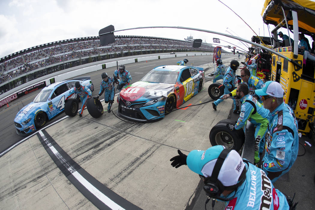 Kyle Busch (18) and Kevin Harvick (4) make pit stops during a NASCAR Cup Series auto race at Po ...