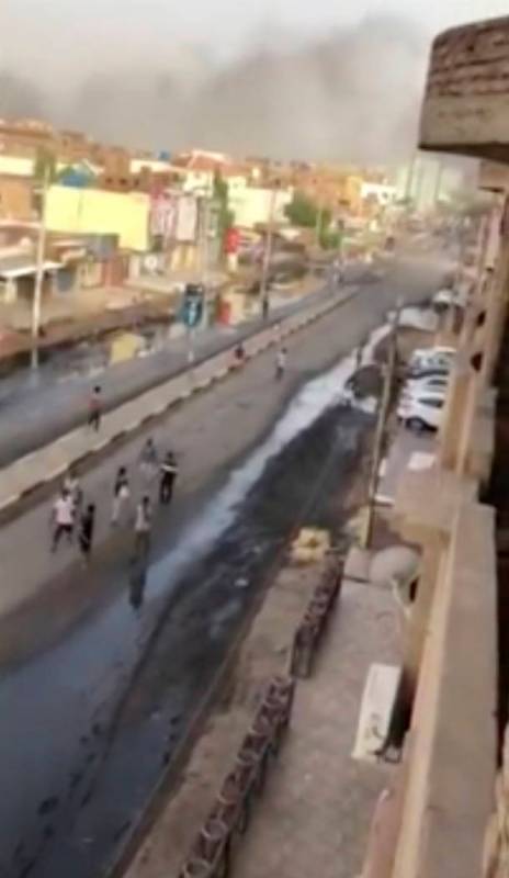 In this image made from video, civilians walk down a street in Khartoum, Sudan with plumes of s ...