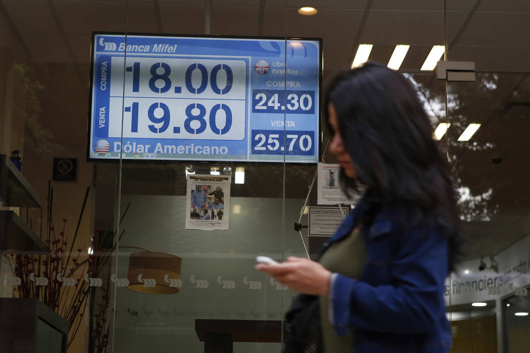 A sign displays exchange rates on a storefront window in Mexico City, Mexico, Friday, May 31, 2 ...