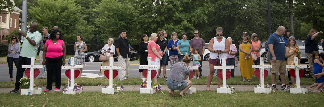 Community members stand by the 12 crosses at the memorial located by Building 11 of the Virgini ...