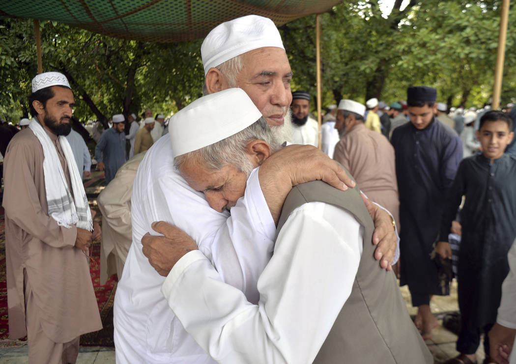 Pakistani Muslims greet each other after offering the Eid al-Fitr prayers, which marks the end ...