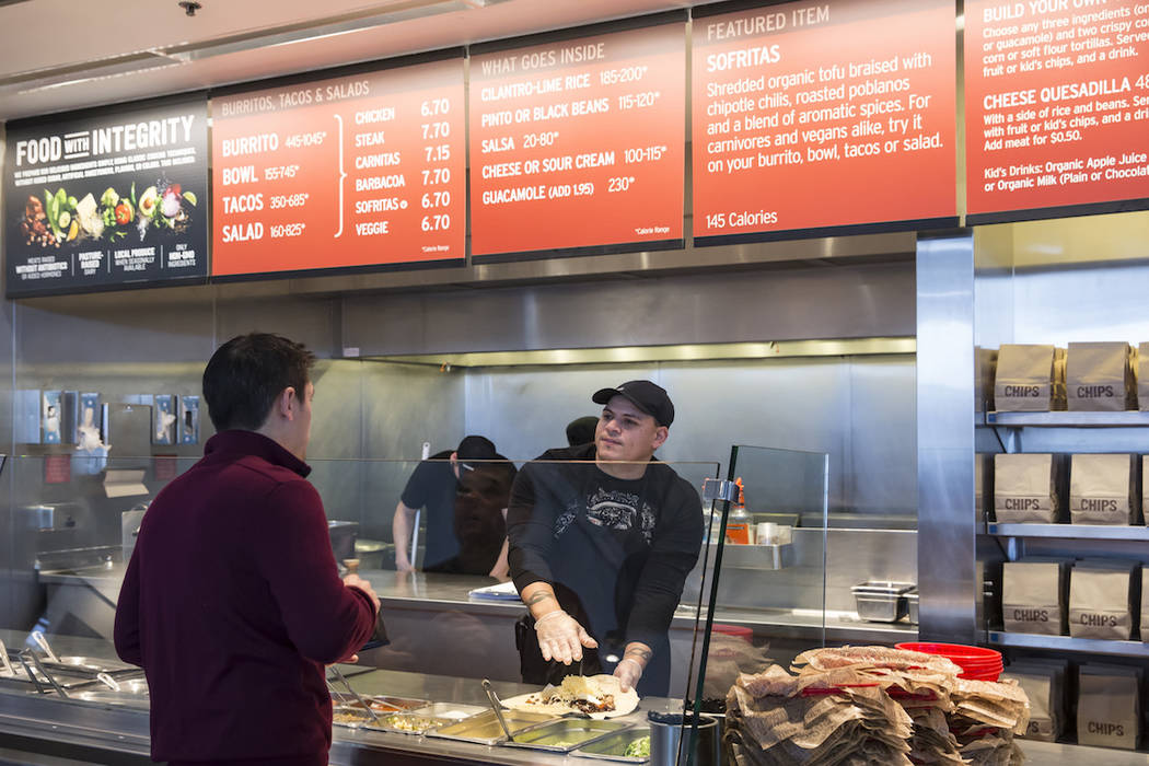 In this Dec. 15, 2015 file photo, a Chipotle Mexican Grill employee, right, prepares a burrito ...