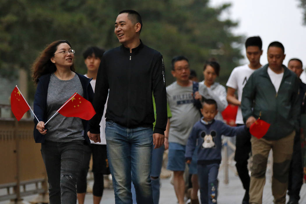 People hold Chinese national flags leave Tiananmen Square after attending the daily flag raisin ...