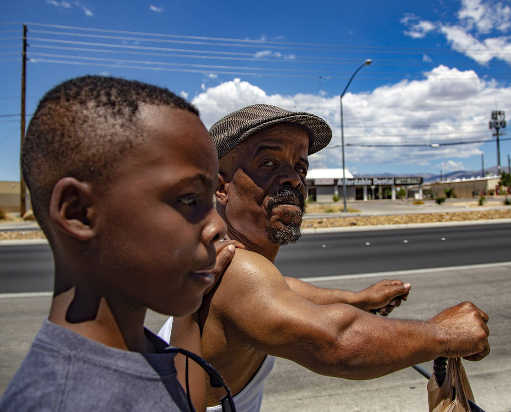 Emmanuel Worthington, 58, of North Las Vegas walks back home with his Grandson, Jaiden Jackson, ...