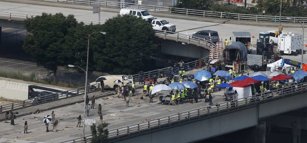 In this July 8, 2014 photo, actors and extras work during filming of the "The Walking Dead," in ...