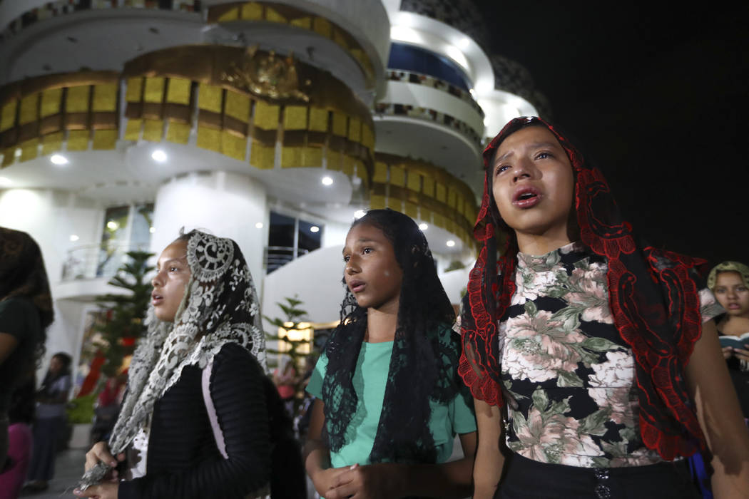 Young women pray outside the "La Luz Del Mundo," or Light of the World church, after members le ...