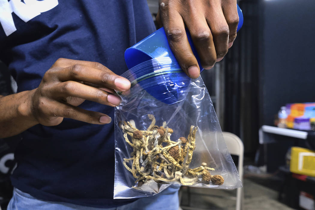 In this Friday, May 24, 2019 photo a vendor bags psilocybin mushrooms at a cannabis marketplace ...