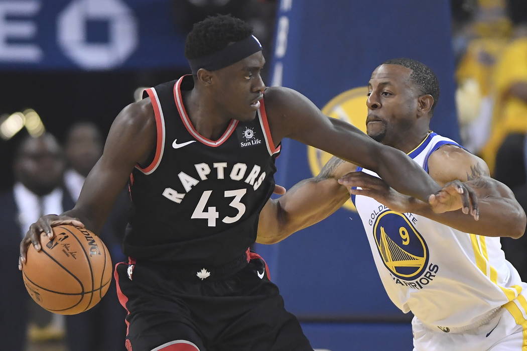 Toronto Raptors forward Pascal Siakam (43) holds off Golden State Warriors forward Andre Iguoda ...