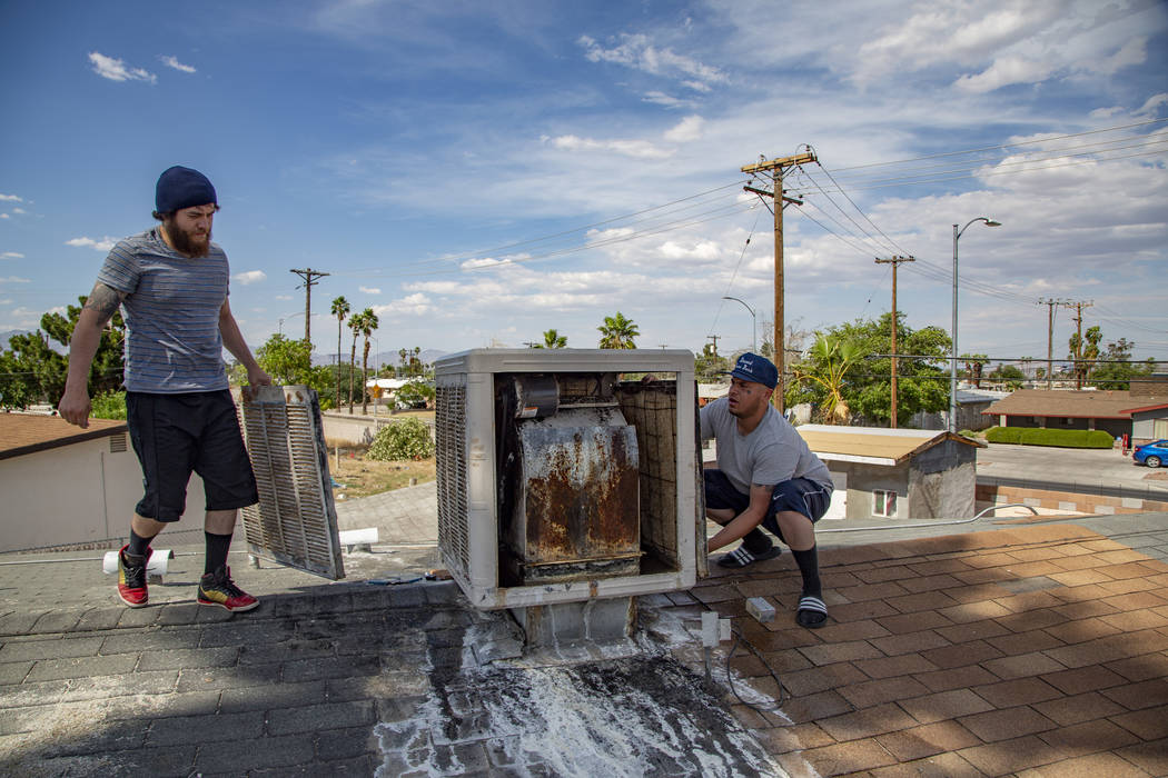 Jose Jesus Gomez, 23, and Sergio Soderanis, 27, fix the swan cooler on their roof as temperatur ...